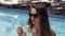 Young beautiful girl drinks coffee by the blue pool