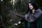 Young beautiful girl in green raincoat, looks as witch on Halloween in forest