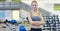 Young beautiful girl in the gym, stands smiling with a towel on her shoulder after the coaching and relaxed. Concept: to love spor