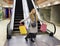 Young beautiful girl is happy against a background of an escalator in a shopping center with shopping bags