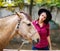 Young beautiful girl in a hat and shirt stroking a horse. Outside.