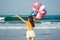 Young and beautiful girl holding an air helium ball on the sea. concept of holiday and vacation. balloons, girl, dawn