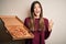 Young beautiful girl holding delivery box with Italian pizza standing over white background screaming proud and celebrating