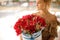 Young beautiful girl holds in hands big round box with red flowers.