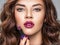 Young beautiful girl holds purple lipstick close to face
