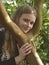A young beautiful girl holds the trunk of a tree in her arms and smiles