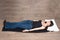Young beautiful girl in jeans and a black top is tired of work, relaxing on the floor, straightens her back, relax