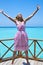 Young beautiful girl jumps in pink sundress on platform of villa on water, Maldives