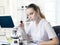 Young beautiful girl lab assistant looks in a microscope in a la
