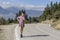 Young, beautiful girl in a lilac dress on the roadway in the mountains with a phone in her hands on a sunny day