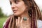 Young beautiful girl with long dreadlocks holds in hand anyolite natural stone outdoors during morning near her face