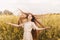 Young beautiful girl with long hair flying in the wind against the background of rapeseed field. Breeze playing with girl`s hair