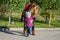 Young beautiful girl with long hair in a jacket mother teaches his daughter to walk their baby\'s first steps outdoors on a sunny d