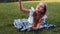 Young beautiful girl making selfie portrait using smartphone in green park, lying on the grass with mobile phone. Color