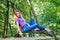 Young beautiful girl model of European appearance with long hair in a shirt and jeans sitting on a tree during a walk in the