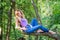 Young beautiful girl model of European appearance with long hair in a shirt and jeans sitting on a tree during a walk in the