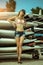 Young beautiful girl at old surfing and windsurfing station stands near the surfboards installed on the racks outdoor