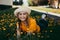 Young beautiful girl in an orange T-shirt lying on the lawn where dandelions grow, flowering dandelions