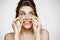 Young beautiful girl with perfect clean skin smiling holding cucumber slices over white background. Beauty cosmetology