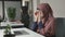Young beautiful girl in pink hijab puts on glasses and starts working on the computer. Arab women in the office 60 fps