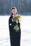 Young beautiful girl posing outside in the winter with a bouquet of tulips in a black