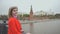 Young beautiful girl in a red coat posing on the bridge on the background Red Square, Moscow Kremlin, Russia