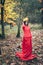 Young beautiful girl in red dress with crown of autumn yellow le