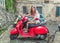 Young beautiful girl rides a red motor scooter Vespa through the streets of Rome, Italy