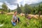 Young beautiful girl shepherd grazes a herd of sheeps in a green field