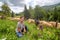 Young beautiful girl shepherd grazes a herd of sheeps in a green field