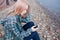 Young beautiful girl sitting on the beach and listening to music on your smartphone