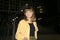 Young beautiful girl sitting in a bench in a public city park at night while looking to camera