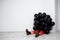 Young beautiful girl sitting in black baloons over white wall.