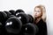 Young beautiful girl sitting in black baloons over white wall.