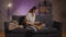 Young beautiful girl sitting on the couch working on a laptop. Girl talking on the phone