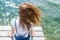 Young beautiful girl sitting on jetty river on background