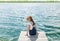 Young beautiful girl sitting on jetty river on background