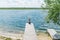 Young beautiful girl sitting on jetty river on background