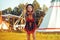 Young beautiful girl smiling on background teepee, tipi- native indian house. Pretty girl in hat with long cerly hair