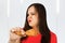 Young beautiful girl sniffs fast food a chicken leg and think