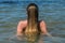 Young beautiful girl sprays water with hair in the form of a circle in the sea