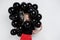 Young beautiful girl standing in black baloons over white wall.