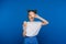 A young beautiful girl standing on a blue background holds lemons in her hands and covers her eyes with them