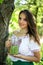 Young beautiful girl stands with a pitcher of green peas near the tree