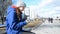 Young beautiful girl student drinks coffee on the street in the cold season and writes a message to friends