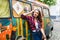 Young beautiful girl in stylish clothes in front of old broken bus posing in city street