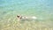 Young beautiful girl swims lying on her back in the blue clean sea