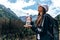 Young beautiful girl traveler in white hat and black jacket and backpack, standing with closed eyes and holding a bottle