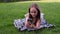 Young beautiful girl using phone lies on grass in the park