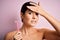 Young beautiful girl using shaver for depilation standing over isolated pink background stressed with hand on head, shocked with